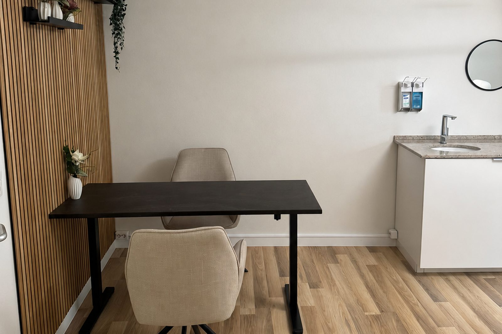 Beratungsraum mit Schreibtisch, zwei Stühlen und Holzlamellenwand